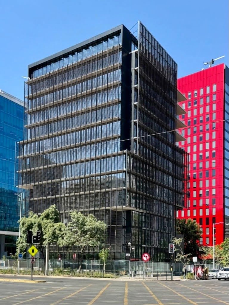 Fachada del edificio Workhub Manquehue, con su celosía de lamas metálicas, en Av. Manquehue Norte