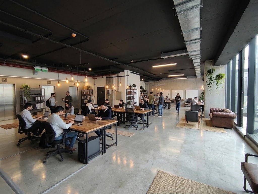 Oficina del piso -1 con escritorios compartidos, zona de estar y ventanales